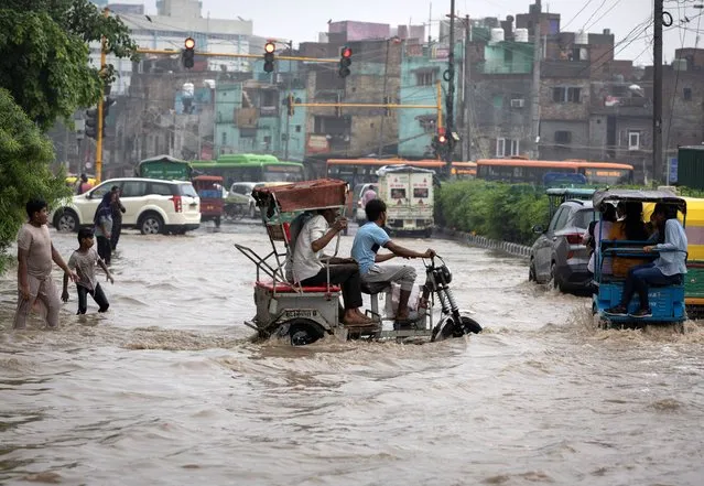 A man rides his battery rickshaw through a flooded road after heavy rains in New Delhi, India on July 8, 2023. (Photo by Adnan Abidi/Reuters)