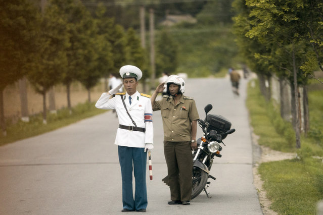 Members of the North Korean military salute the motorcade carrying U.S. Secretary of State Mike Pompeo as it makes its way to the Park Hwa Guest House in Pyongyang, North Korea, Friday, July 6, 2018. Pompeo is on a trip traveling to North Korea, Japan, Vietnam, Abu Dhabi, and Brussels. (Photo by Andrew Harnik/AP Photo)