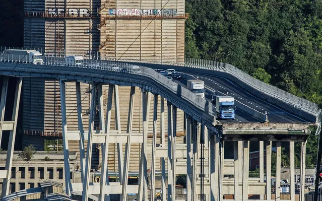 Cars and trucks are left on a section of the collapsed Morandi highway bridge in Genoa, northern Italy, Wednesday, August 15, 2018. A bridge on a main highway linking Italy with France collapsed in the Italian port city of Genoa during a sudden, violent storm, sending vehicles plunging 90 meters (nearly 300 feet) into a heap of rubble below. (Photo by Nicola Marfisi/AP Photo)