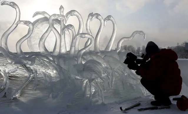 A cameraman takes video of an ice sculpture called "The Melody of Sunset", created by participants from the city of Barnaul, during the annual International festival of snow and ice sculptures "The Magical Ice of Siberia", on an embankment of the Yenisei river, with the air temperature at about minus 26 degrees Celsius (minus 14.8 degrees Fahrenheit), in Krasnoyarsk, Siberia, Russia, January 16, 2016. (Photo by Ilya Naymushin/Reuters)