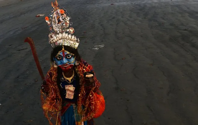 A Hindu devotee, dressed as the Hindu goddess Kali, begs for alms at Gangasagar Island, India, January 12, 2016. (Photo by Dibyangshu Sarkar/AFP Photo)