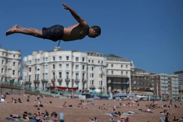 A man dives into the sea as people enjoy the hot weather on Brighton beach, in Brighton, Britain, June 1, 2021. (Photo by Hannah McKay/Reuters)