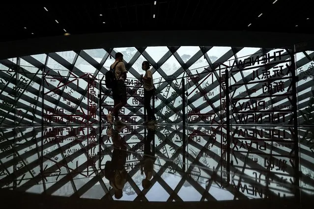 A couple wearing face masks to help curb the spread of the coronavirus is silhouetted as they chat each other at a shopping mall in Beijing, Sunday, June 6, 2021. (Photo by Andy Wong/AP Photo)