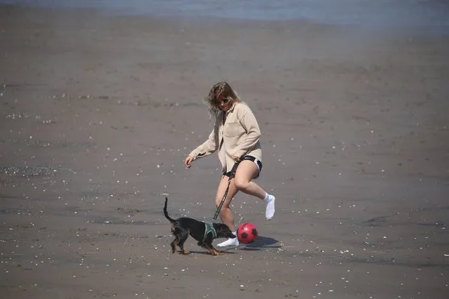 A woman plays football with a dog on Portobello beach, near Edinburgh on Monday, May 31, 2021, as Bank Holiday Monday could be the hottest day of the year so far – with temperatures predicted to hit 25C in parts of the UK. (Photo by Andrew Milligan/PA Images via Getty Images)