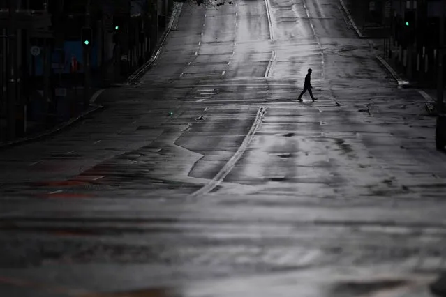 A pedestrian crosses an empty street in Sydney, Australia, 29 June 2021. More than five million people in Greater Sydney and its surrounds have gone into a 14-day lockdown as health authorities try to regain control of a coronavirus outbreak. (Photo by Mick Tsikas/EPA/EFE)