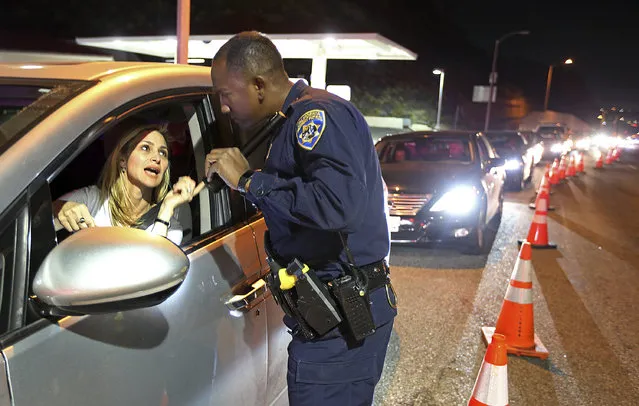 California Highway patrol Officer S. Kizito verifies that a woman seeking to return to Malibu in Southern California is an actual resident after Woolsey Fire evacuation orders were lifted for the eastern portion of the city Tuesday evening, November 13, 2018. (Photo by Reed Saxon/AP Photo)
