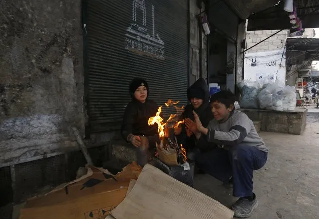Children warm themselves around a fire in al-Sukari neighborhood of Aleppo January 8, 2015. (Photo by Hosam Katan/Reuters)