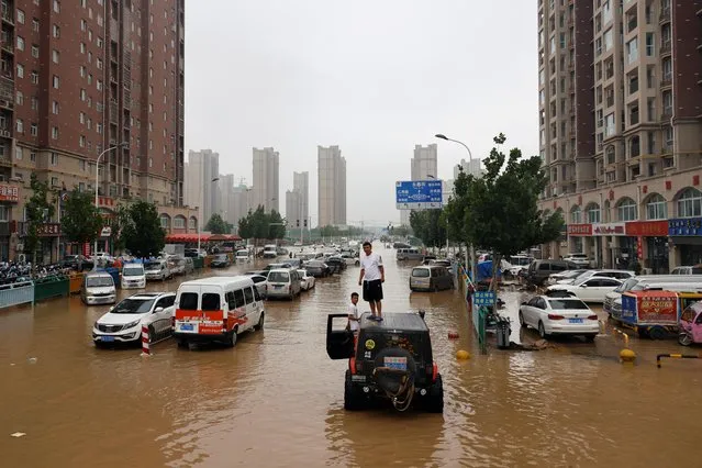 Men stand on a vehicle on a flooded road following heavy rainfall in Zhengzhou, Henan province, China on July 23, 2021. (Photo by Aly Song/Reuters)