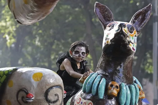 A child rides on a float during a James Bond-inspired Day of the Dead Parade, in Mexico City, Saturday, November 4, 2023. The Hollywood-style parade was adopted in 2016 by Mexico City to mimic a fictitious march in the 2015 James Bond movie “Spectre”. (Photo by Ginnette Riquelme/AP Photo)