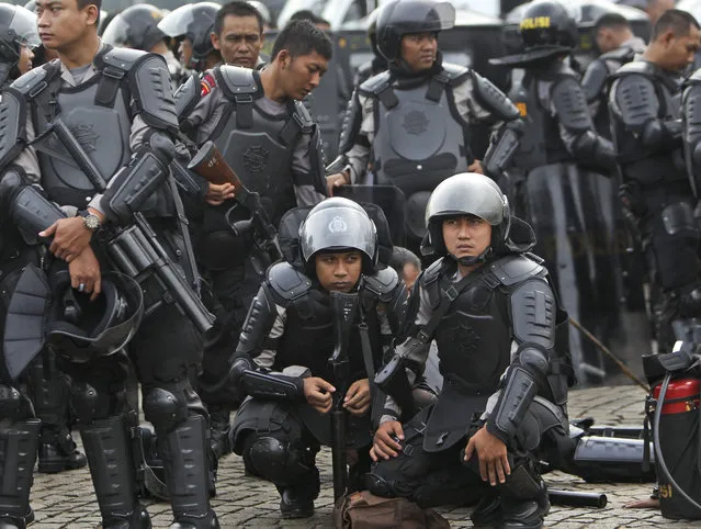 Indonesian police officers in riot gears take a break during a show of force ahead of Christmas celebrations in Jakarta, Indonesia, Friday, December 20, 2013. Since the Bali bombings in 2002, the world's largest Muslim country has been battling terrorists who recently operate in small groups and have targeted security forces and local “infidels” instead of Westerners. (Photo by Tatan Syuflana/AP Photo)