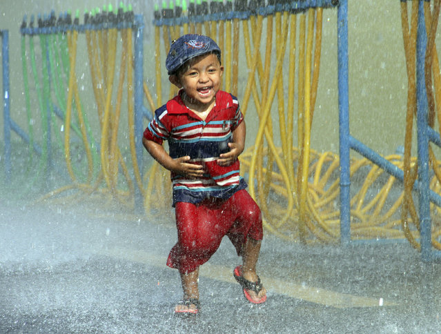 A boy runs as he is splashed with water during the opening ceremony of the annual Thingyan water festival celebrations outside Yangon City Hall in Yangon, Myanmar Monday, April 13, 2015. Myanmar began celebrating its annual days-long water festival, known as Thingyan, on Monday, marking the new year according to the traditional Burmese lunisolar calendar. (Photo by Khin Maung Win/AP Photo)