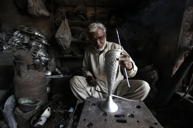A craftsman works on a silver flowerpot at a workshop in Lahore, Pakistan February 2, 2016. (Photo by Mohsin Raza/Reuters)