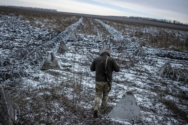 A Ukrainian serviceman walks along defense structures near a front line in the Kharkiv Region, Ukraine on December 25, 2023. (Photo by Viacheslav Ratynskyi/Reuters)