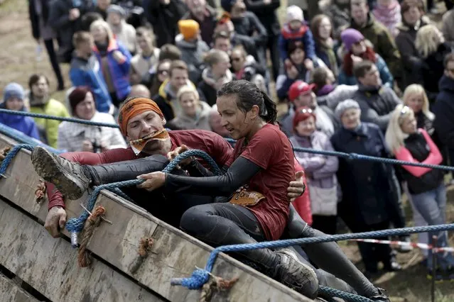 Participants help each other as they compete during the Strong Race event near Tukums, Latvia, May 3, 2015. (Photo by Ints Kalnins/Reuters)