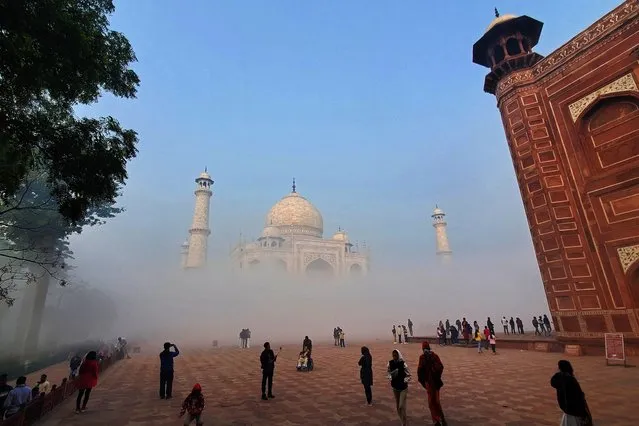 Tourists visit the Taj Mahal engulfed in fog on a winter morning in Agra on December 24, 2023. (Photo by Pawan Sharma/AFP Photo)