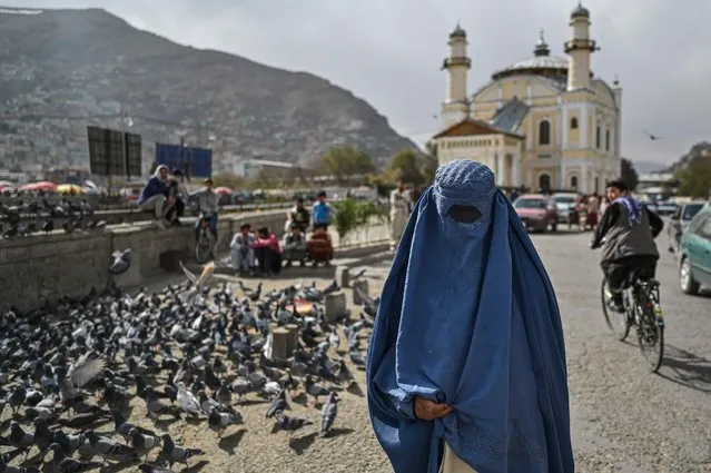 An Afghan burqa-clad woman walks on a street in Kabul city, on October 29, 2021. (Photo by Hector Retamal/AFP Photo)