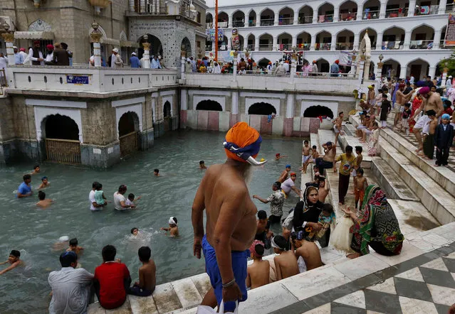 A Sikh pilgrim leaves after taking a holy bath during the Vasakhi festival, at the shrine of Gurdwara Punja Sahib, the second most sacred place for Sikhs, in Hasan Abdal, some 50 kilometers (31 Miles) from Islamabad, Pakistan, Sunday, April 14, 2019. Thousands of Sikh pilgrims arrived from neighboring India and other countries to attend the harvest festival that is regionally known by many names and marks the Solar New Year. (Photo by Anjum Naveed/AP Photo)