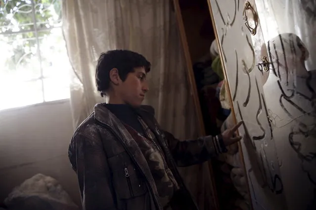 A boy writes on a dusty mirror in a damaged house in the rebel held besieged city of Douma, a suburb of Damascus, Syria February 27, 2016. (Photo by Bassam Khabieh/Reuters)