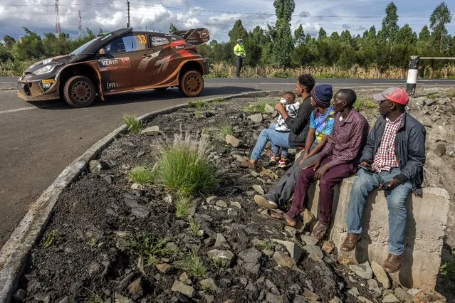 People look on at the side of a road as Toyota Gazoo Racing WRT's British driver Elfyn Evans steers his Toyota GR Yaris Rally1 Hybrid with British co-driver Scott Martin while arriving to Naivasha ahead of the second day of the World Rally Championship (WRC) Safari Rally Kenya in Naivasha, on March 28, 2024. (Photo by Luis Tato/AFP Photo)