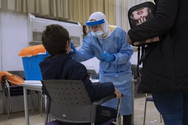 A child is tested for the coronavirus by a healthcare worker at a COVID-19 testing center in Ramat Gan, Israel, Sunday, January 2, 2022. Israel's Prime Minister Naftali Bennett on Sunday warned the country will soon see tens of thousands of new coronavirus cases a day. (Photo by Oded Balilty/AP Photo)