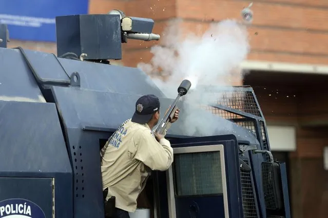 A National Police member shoots tear gas during clashes in an anti-government protest in Caracas on March 22, 2014. Thousands of Venezuelans demonstrated in Caracas to denounce alleged dictatorial actions of the government while a crowd of pro-Chavez students marched against “fascist violence”, in the framework of a month and a half of protests which left 31 dead so far. (Photo by Leo Ramirez/AFP Photo)