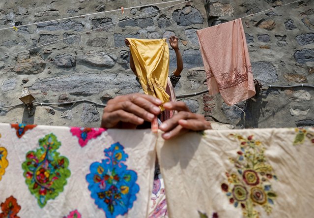 Washermen leave embroidered shawls to dry in the sun, on the banks of river Jhelum, in Srinagar on April 24, 2024. (Photo by Sharafat Ali/Reuters)