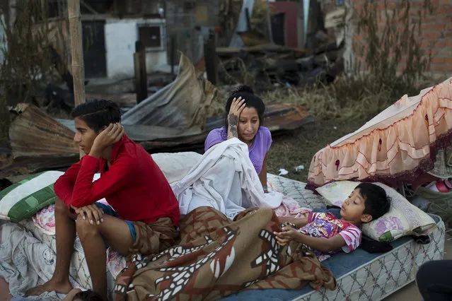 A family wake up after sleeping outside their collapsed home, destroyed by an earthquake in Manta, Ecuador, Tuesday, April 19, 2016. (Photo by Rodrigo Abd/AP Photo)