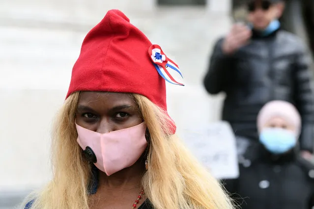 A protester wears a face mask and a Phrygian hat, depicted on statues and imagery of France's Marianne, during a demonstration against a bill dubbed as “anti-separatism” and islamophobia in Paris on March 21, 2021. A divisive debate takes place in France about what French President has termed “Islamist separatism”, in which Islamists are said to be flouting French laws in closed-off Muslim communities and fuelling terror attacks on French soil. The lower house of parliament approved a tough draft law that will extend the state's powers to shut down religious groups judged to be extremist. (Photo by Alain Jocard/AFP Photo)