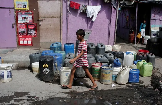 A girl walks past the empty water containers kept by the residents to collect free drinking water from a municipal tanker in New Delhi, India, June 28, 2019. (Photo by Adnan Abidi/Reuters)