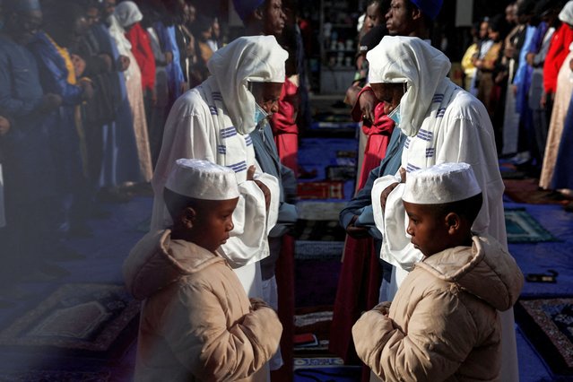 The reflection of a man and a boy is seen as people pray outside the Masjid At-Taqwa mosque on the sidewalk, during Eid al-Fitr, which marks the end of the Muslim holy fasting month of Ramadan, in the Bedford-Stuyvesant section of the Brooklyn borough of New York City, New York, U.S., April 10, 2024. (Photo by Shannon Stapleton/Reuters)