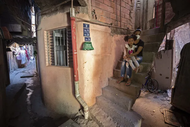 Ana Carolina Silva, who lost her job during the COVID-19 pandemic, sits with her daughter Cataleia outside her home in the Paraisopolis favela of Sao Paulo, Brazil, Monday, May 24, 2021. (Photo by Andre Penner/AP Photo)