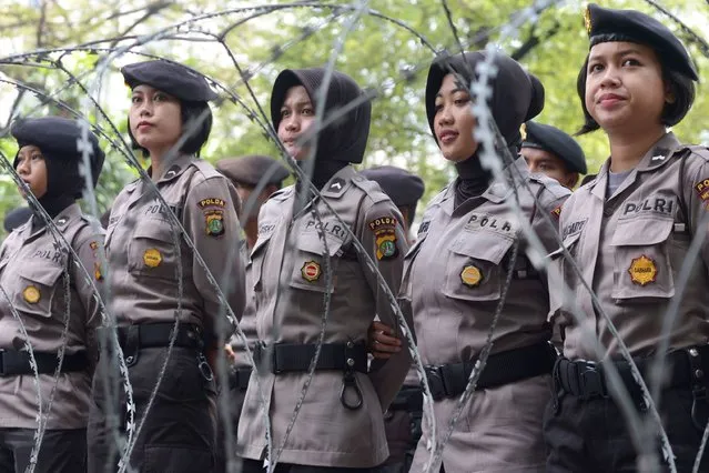 Indonesian policewomen stand in formation behind barbed wire as demonstrators participate in a May Day protest in Jakarta on May 1, 2017. Millions of May Day demonstrators took to the streets across the country as they demanded better social security while rejecting outsourcing policies and low wages. (Photo by Adek Berry/AFP Photo)