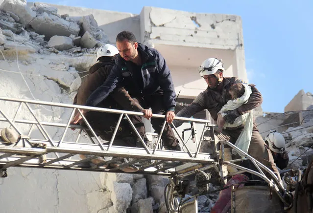 Syrian Civil Defence members evacuate a toddler from the rubble of buildings destroyed following Russian air strikes a day earlier on the northwestern city of Idlib, on May 31, 2016. (Photo by Omar Haj Kadour/AFP Photo)