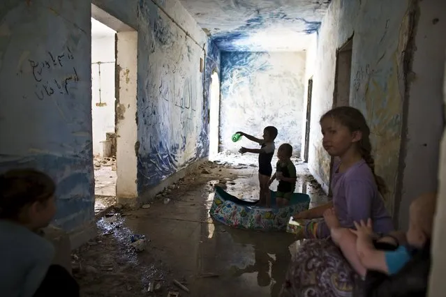 Children play in a plastic pool inside an abandoned building at the evacuated settlement of Sa-Nur in the West Bank July 28, 2015. About 250 right wing protesters defied an Israeli Defense Force (IDF) decree and entered the former West Bank settlement of Sa-Nur Israel evacuated during the 2005 disengagement. (Photo by Nir Elias/Reuters)