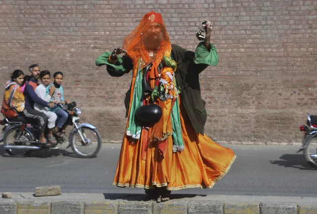 A Muslim dervish sings a traditional Sufi song near a rally for the Mawlid al-Nabi holiday, marking the birthday of Islam's prophet, Muhammad, in Lahore, Pakistan, Sunday, November 10, 2019. To mark the holiday, thousands take part in religious processions, ceremonies and distribute free meals to the poor. (Photo by K.M. Chaudary/AP Photo)