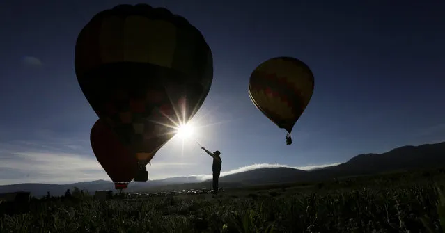 Balloons launch from a field at sunrise during the Balloons over Angel Fire festival, Sunday, June 18, 2017, in Angel Fire, New Mexico. (Photo by Eric Gay/AP Photo)
