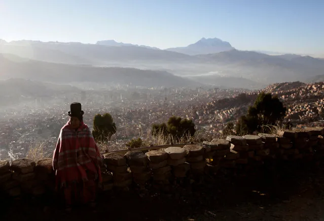 A Bolivian indigenous woman sits in El Alto with La Paz city in the background, Bolivia, June 21, 2016. (Photo by David Mercado/Reuters)