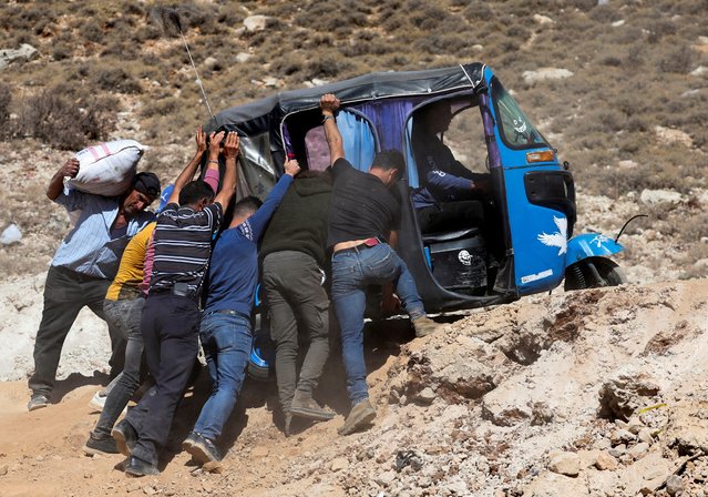 People push a tuk-tuk while crossing from Lebanon into Syria, as they flee the ongoing hostilities between Hezbollah and Israeli forces, at Masnaa border crossing, Lebanon on October 28, 2024. (Photo by Mohamed Abd El Ghany/Reuters)