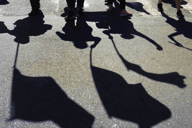 Union workers' shadows are cast on the street as they march with flags on International Workers' Day in Asuncion, Paraguay, May 1, 2024. (Photo by Jorge Saenz/AP Photo)