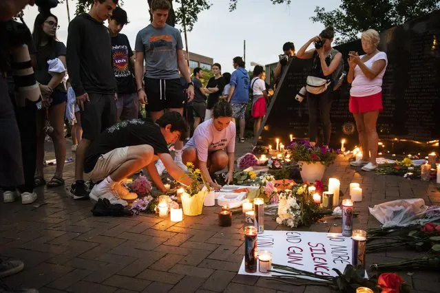 Dozens of mourners gather for a vigil near Central Avenue and St. Johns Avenue in downtown Highland Park, one day after a gunman killed at least seven people and wounded dozens more by firing an AR-15-style rifle from a rooftop onto a crowd attending Highland Park's Fourth of July parade, Tuesday, July 5, 2022 in Highland Park, Ill.. (Photo by Ashlee Rezin/Chicago Sun-Times via AP Photo)