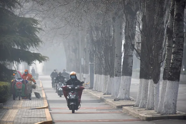 People wear face masks as they ride along a road in Beijing, Friday, February 21, 2020. Chinese health officials expressed new optimism Thursday over the deadly virus outbreak while authorities in South Korea’s fourth-largest city urged residents to hunker down as fears nagged communities far from the illness’ epicenter. (Photo by Mark Schiefelbein/AP Photo)