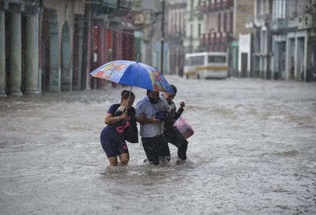 People wade through a flooded street of Havana, on June 8, 2022, following heavy rains in the island nation. Heavy rains from the remnants of Hurricane Agatha flooded much of western Cuba last week, killing at least three people in Havana. (Photo by Yamil Lage/AFP Photo)