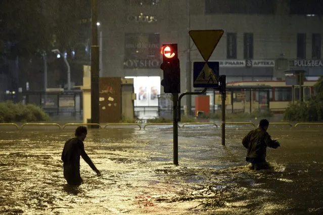 A view of people wading in a flooded street during a downpour in Gdansk, northern Poland, 15 July 2016. Heavy raining hit throughout 14 and 15 July causing lots of damage to buildings, trees, electricity, flooding streets and roads. (Photo by Adam Warzawa/EPA)