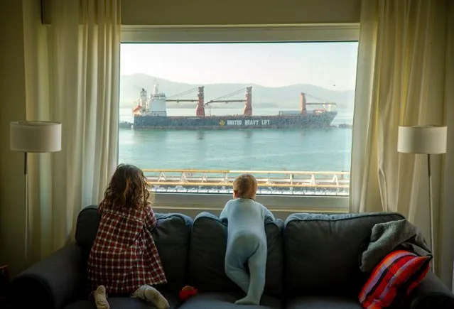Two young girls look at the merchant ships docking at the port from the window of their house, during the coronavirus emergency lockdown, in Santander, Spain, 25 March 2020. Spain is on its 11th consecutive day of national lockdown imposed by the government in an attempt to slow down the spread of the pandemic COVID-19 disease caused by the SARS-CoV-2 coronavirus. (Photo by Roman G. Aguilera/EPA/EFE)