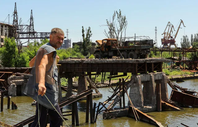 A fisherman stands on a bridge near the Azovstal steel mill during Ukraine-Russia conflict in the southern port city of Mariupol, Ukraine on July 15, 2022. (Photo by Alexander Ermochenko/Reuters)