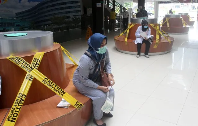 Visitors sit on social distancing benches at a hospital to prevent the spread of coronavirus disease (COVID-19) in Padang, West Sumatera Province, Indonesia on March 21, 2020. (Photo by Muhammad Arif Pribadi/Antara Foto via Reuters)