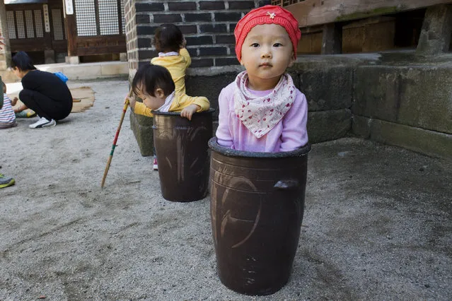 Jung Ha-yoon, 2, appears to be stuck inside a ceramic container while playing with other children at the traditional sports square during the “Taste Korea! Korean Royal Cuisine Festival” held at Unhyeon Palace, also known as Unhyeongung Royal Residence, in Seoul, South Korea, on Tuesday, October 1 2013. (Photo by Jacquelyn Martin/AP Photo)