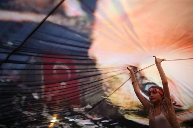 A Turkish girl helps to hold up a huge picture of modern Turkey's founder Mustafa Kemal Ataturk at a rally in Gundogdu Square in Izmir on August 4, 2016, protesting against the failed July 15 military coup attempt, with the participation of Republican People's Party (CHP) leader Kemal Kilicdaroglu (not pictured). Turkey issued an arrest warrant on August 4 for US-based preacher Fethullah Gulen, accusing him of ordering the coup attempt aimed at ousting President Recep Tayyip Erdogan. An Istanbul court issued the warrant, the first after the failed putsch for the reclusive cleric in Pennsylvania, the Anadolu news agency said. (Photo by Emre Tazegul/AFP Photo)