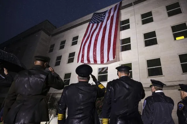 First responders look as an American flag is unfurled on the side of the Pentagon to commemorate the anniversary of the 9/11 terror attacks September 11, 2022 in Arlington, Virginia. The nation is marking the 21st anniversary of the terror attacks that took almost 3000 lives. (Photo by Oliver Contreras/The Washington Post)