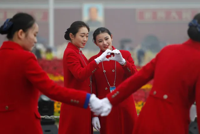 Ushers pose for photos at the Tiananmen Square during the opening of the 19th National Congress of the Communist Party of China at the Great Hall of the People in Beijing, China October 18, 2017. (Photo by Ahmad Masood/Reuters)